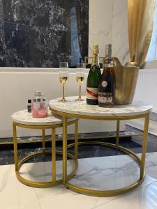 Duas mesas com garrafas de vinho e copos. em Apartament "Prezydencki" Centrum z dużą wanną dla Dwojga em Gniezno
