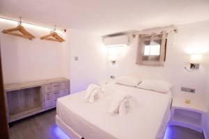 a white bedroom with a bed with towels on it at Primrose Apartments in Astypalaia