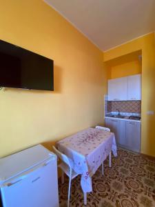 a kitchen with a table and a tv on the wall at Sea View - Beautiful Terrace with BBQ in Triscina