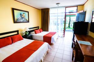 Habitación de hotel con 2 camas y TV en Amapola Resort, en Jacó