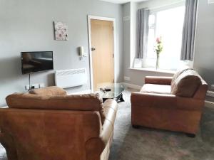 a living room with two couches and a television at Gwynedd House Flat 1 in Pentraeth