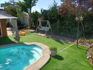 un patio trasero con piscina y césped verde en Casa Rural con Piscina y AA en Sierra Oeste de Madrid, en Pelayos de la Presa