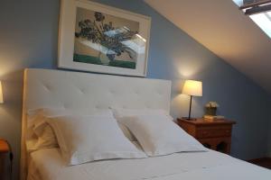 uma cama com almofadas brancas e uma fotografia na parede em Ático muy luminoso con Parking, em Saragoça