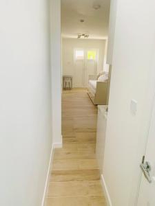 a hallway with white walls and a wooden floor at Lovely en-suite studio with kitchen and free parking with walking distance to tube station and short train ride to central London!! in Northwood