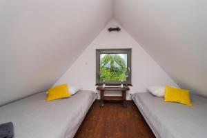 a attic room with two beds and a window at Folwark Żuławski in Elblag