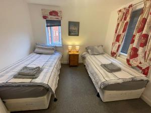 1 Schlafzimmer mit 2 Betten und einem Tisch mit Beleuchtung in der Unterkunft Orchid Cotswold Stone house in Swindon