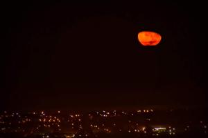 an orange moon in the sky over a city at Marola’s Búzios in Búzios