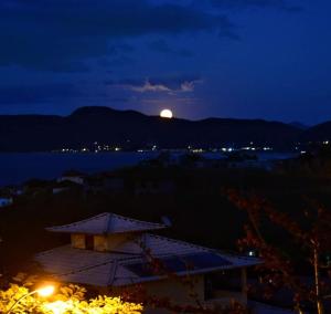 a full moon rising over the water at night at Marola’s Búzios in Búzios