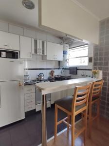 a kitchen with white cabinets and a counter with two chairs at My Place Buenos Aires in Buenos Aires