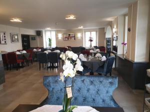 una sala da pranzo con tavoli, sedie e fiori bianchi di LES APPARTEMENTS DE LA B a Saint-Benoît-des-Ondes