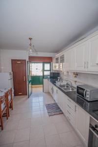Una cocina con gabinetes blancos y encimera. en Charming Private Rooms in an Apartment A2 Penha - Faro, en Faro