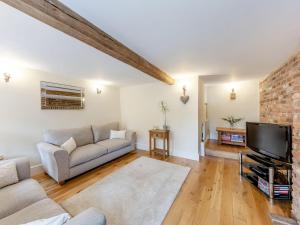 ein Wohnzimmer mit einem Sofa und einem TV in der Unterkunft Bedehouse Cottage in Matlock