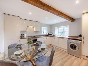 a kitchen with a glass dining table and chairs at Bedehouse Cottage in Matlock