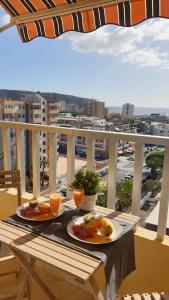 uma mesa com dois pratos de comida e bebidas numa varanda em Preciosas habitaciones en la casa de May em Arona