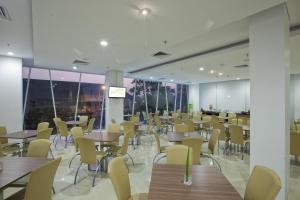 a dining room with tables and chairs and windows at Whiz Hotel Cikini Jakarta in Jakarta