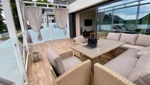 a patio with a couch and a table with a laptop on it at Biały Domek Aleja Lipowa 73D in Zwierzyniec