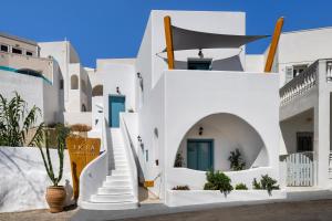 a white building with stairs and plants in front of it at I K I A Since 1980 by Calm Collection in Fira