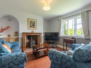 a living room with two blue couches and a table at Eudon Burnell Cottage in Eardington
