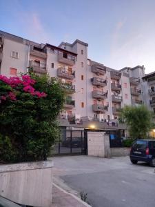 un gran edificio de apartamentos con flores rosas en un aparcamiento en Hauze Trani, en Trani