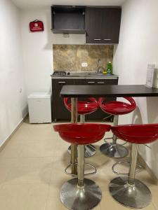 een keuken met twee rode krukken naast een aanrecht bij Lindos apartaestudios y habitaciones en Ibague in Ibagué