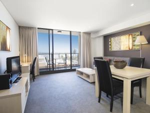 a living room with a dining table and a room with a view at Oaks Adelaide Horizons Suites in Adelaide