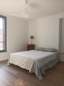a white bedroom with a bed and a lamp at Plein centre, T3, 2ch, balcon et vue in Mèze