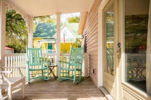eine Veranda mit drei Schaukelstühlen und einem Haus in der Unterkunft Candy Store House by Oak Island Accommodations in Southport