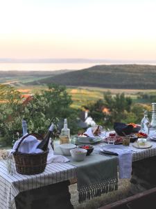 a picnic table with food and bottles of wine at Kis Vulkán Nyúlontúl in Mencshely