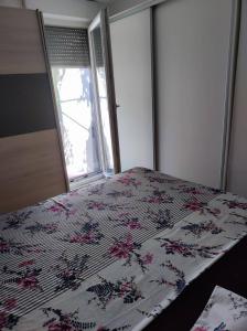 a bedroom with a bed with a floral bedspread and a window at KLM in Split