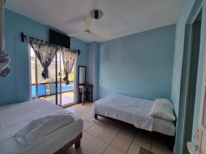 プエルト・エスコンディードにあるCasa La Paz 2の青い壁と窓のある部屋にベッドが2つある +14枚の写真