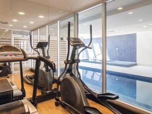 a gym with cardio machines and a swimming pool at Oaks Glenelg Liberty Suites in Adelaide