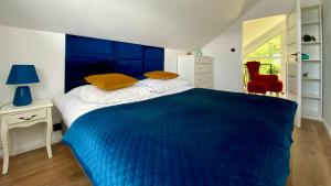 a bedroom with a blue bed and a red chair at Biały Domek Aleja Lipowa 73D in Zwierzyniec +25 photos
