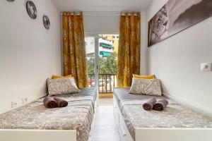 two beds in a room with a window at Cozy main square and beachfront 3-bedrooms apartment in Los Cristianos