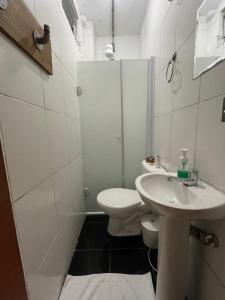 a white bathroom with a toilet and a sink at Studio House Hotel in Sao Paulo