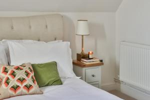 a white bed with a lamp on a night stand at The Rooks Apartment 1 Beverston Castle in Tetbury