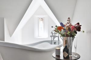 a white bathroom with a vase of flowers and a bath tub at The Rooks Apartment 1 Beverston Castle in Tetbury
