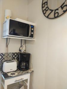 un four micro-ondes installé sur une étagère au-dessus d'une cuisinière dans l'établissement Astéride, parking privé, route des plages, à Quimper
