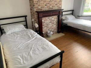 a bedroom with two beds and a brick wall at Ovington Grove 1 free parking fully equipped kitchen 3 bedrooms Netflix in Newcastle upon Tyne