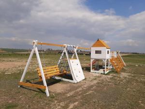 two swings and a play house in a field at Domki Polana in Piotrkowiczki