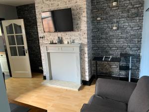 a living room with a tv on a brick wall at Ovington Grove 1 free parking fully equipped kitchen 3 bedrooms Netflix in Newcastle upon Tyne