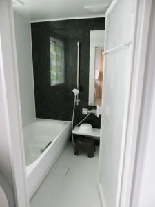 a bathroom with a tub and a toilet and a mirror at 与那覇コテージ　Yonaha Cottage in Yonaha