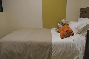 Un dormitorio con una cama con una manta naranja. en Casa Crónica, en Oaxaca City