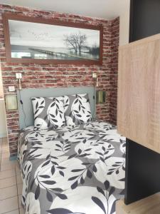 - une chambre avec un lit noir et blanc et un mur en briques dans l'établissement Astéride, parking privé, route des plages, à Quimper
