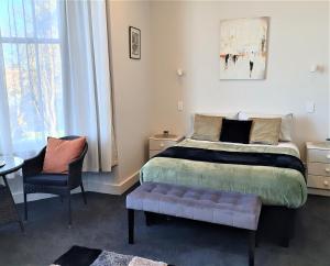 a bedroom with a bed and a chair and a window at Work Stay at 123 in Dunedin +98 photos