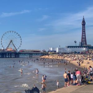 a crowd of people on a beach with a ferris wheel at Blackpool Apartments in Blackpool