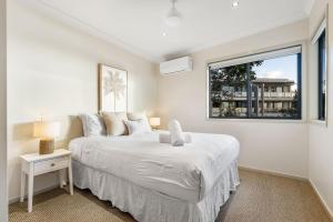 a white bedroom with a large bed and a window at Currumbin Beachside Retreat in Gold Coast