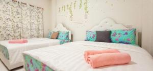 two beds in a room with pink and green at Sweet Floresta Pool Villa in Sattahip