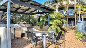 a patio with a table and chairs under a pergola at Sorrento Apartments Merimbula in Merimbula