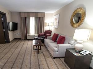 Holiday Inn Charlotte Airport, an IHG Hotel في تشارلوت: غرفة معيشة مع أريكة وكراسي في غرفة في الفندق