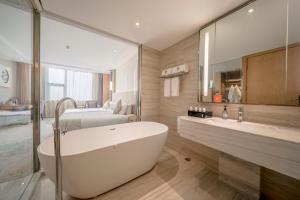 um banheiro com banheira e um quarto em Wuhan Hongguang Hotel em Wuhan